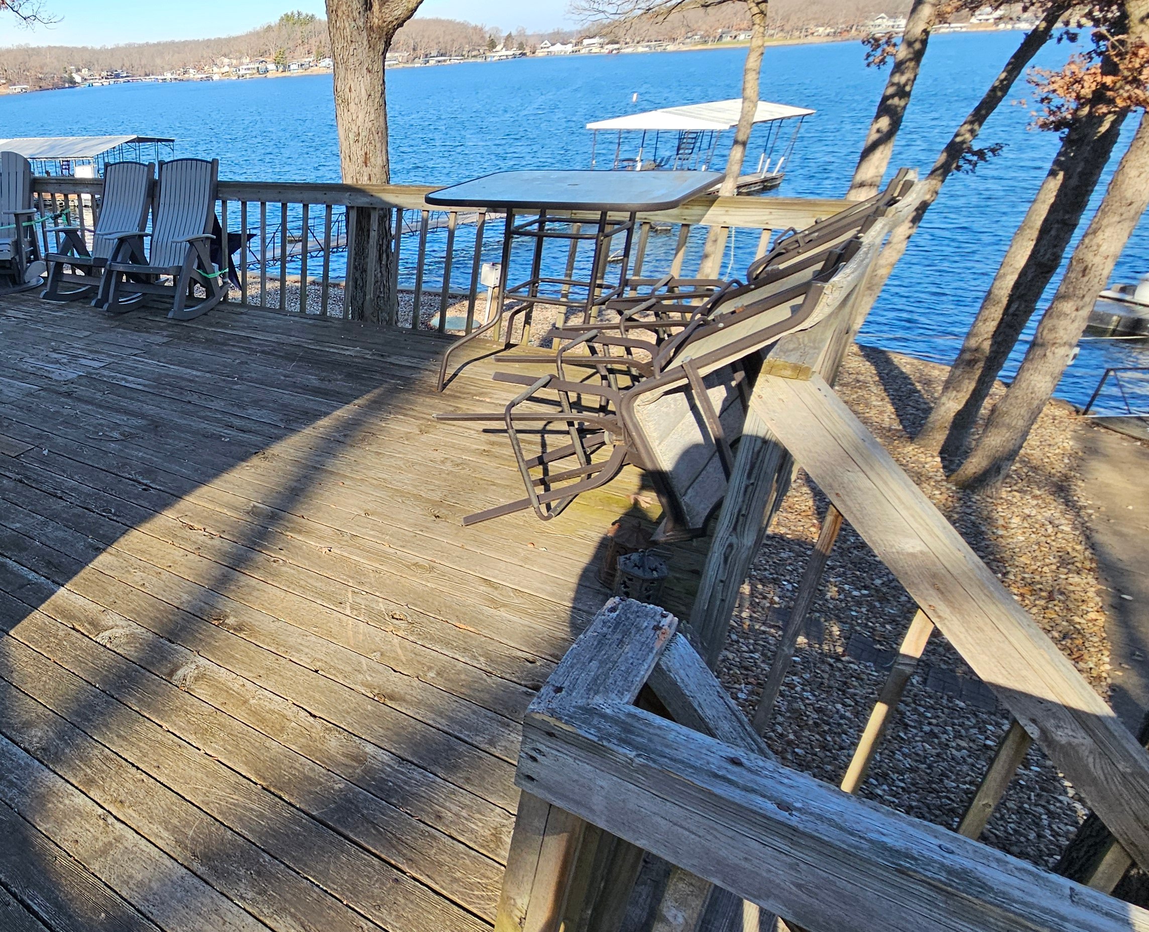 Wooden deck with chairs overlooking a calm blue lake and trees