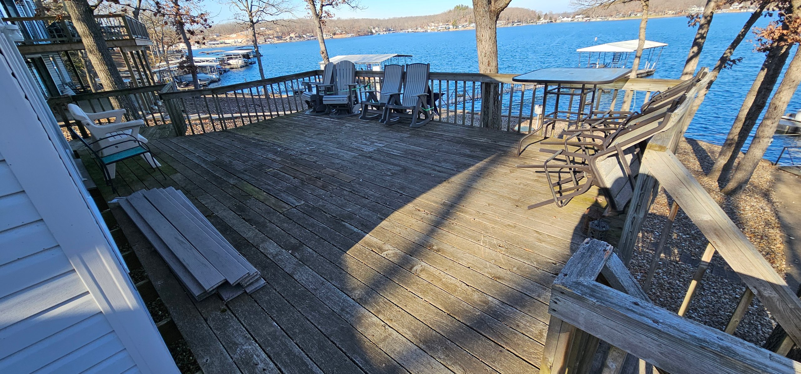 Wooden lakeside deck with chairs overlooking blue water and boats
