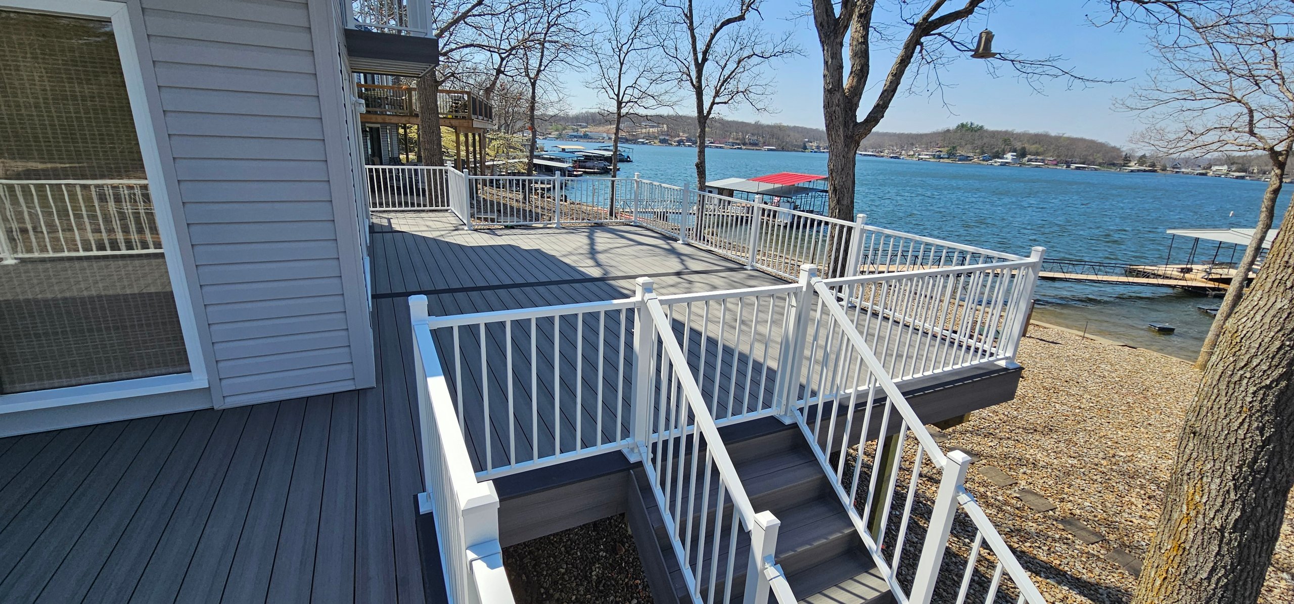 Lakeside deck with white railings and blue-gray decking overlooking water