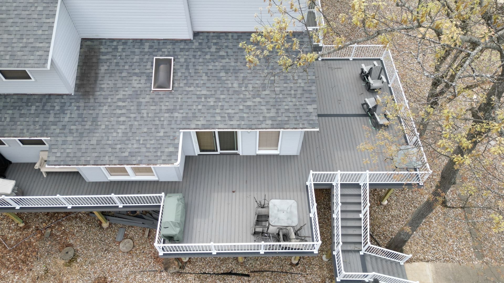 Aerial view of a large gray wooden deck with white railings and stairs