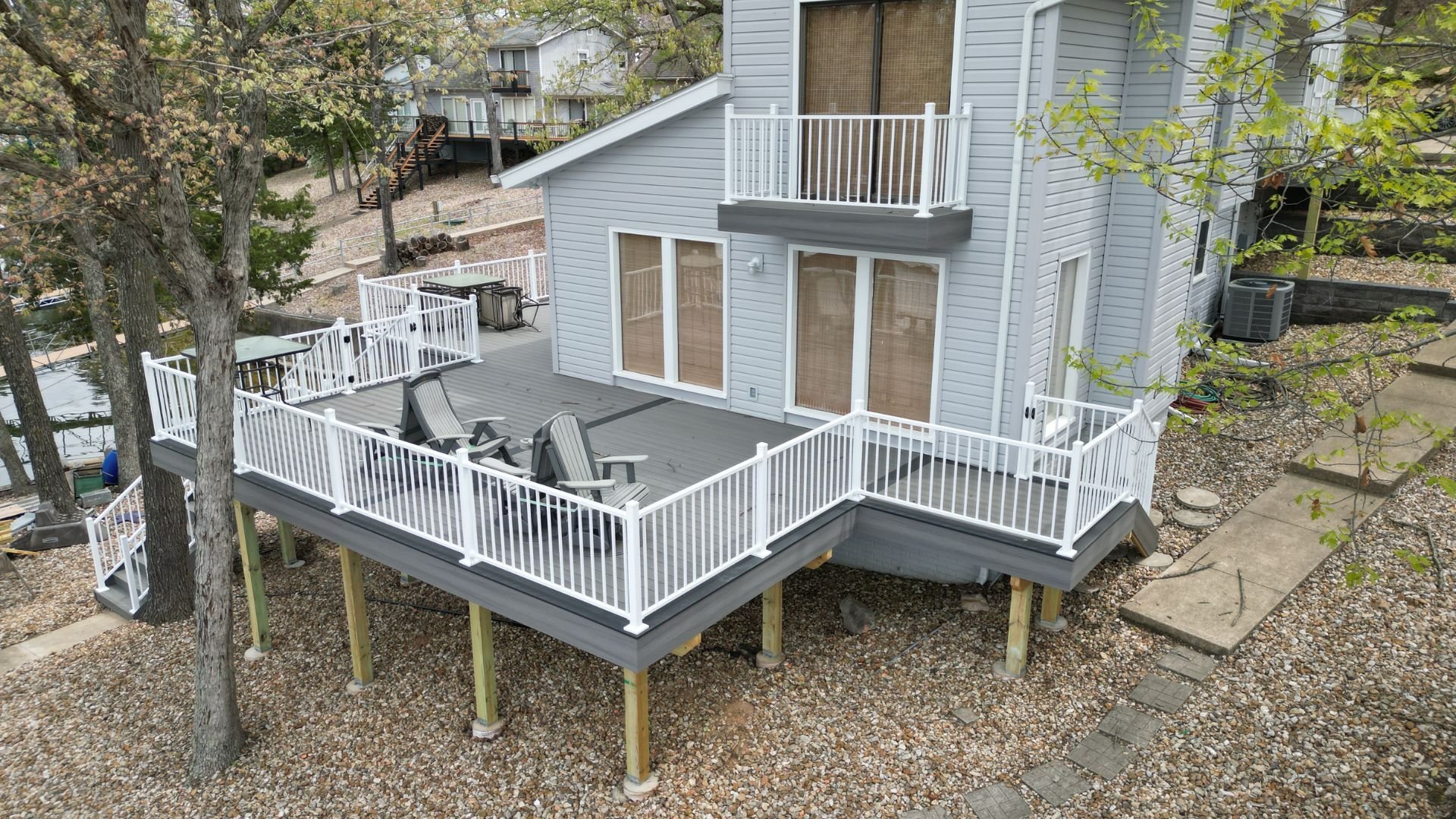 Large multilevel wooden deck with white railings attached to gray house