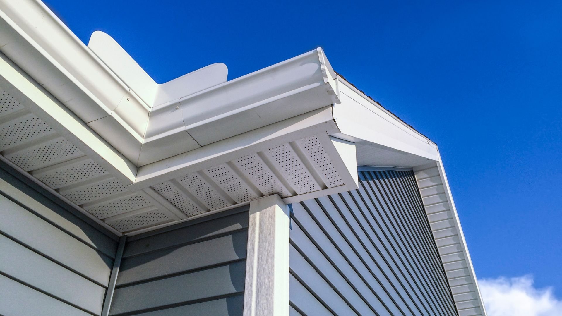 White building roof detail with perforated panels against bright blue sky