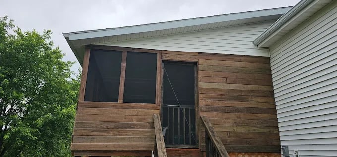 Wooden screen porch with dark screens attached to white sided house