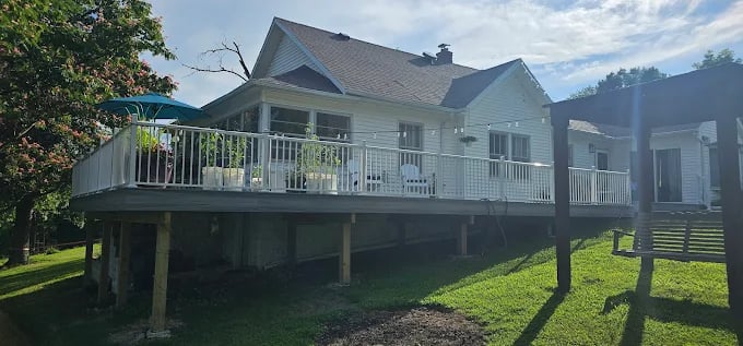 White elevated deck extending from a suburban house with green lawn