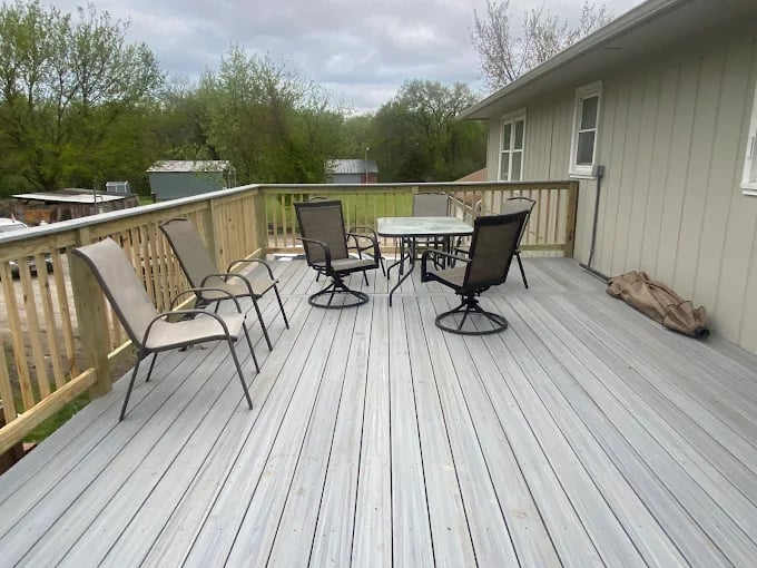 Spacious wooden deck with patio furniture and trees in background