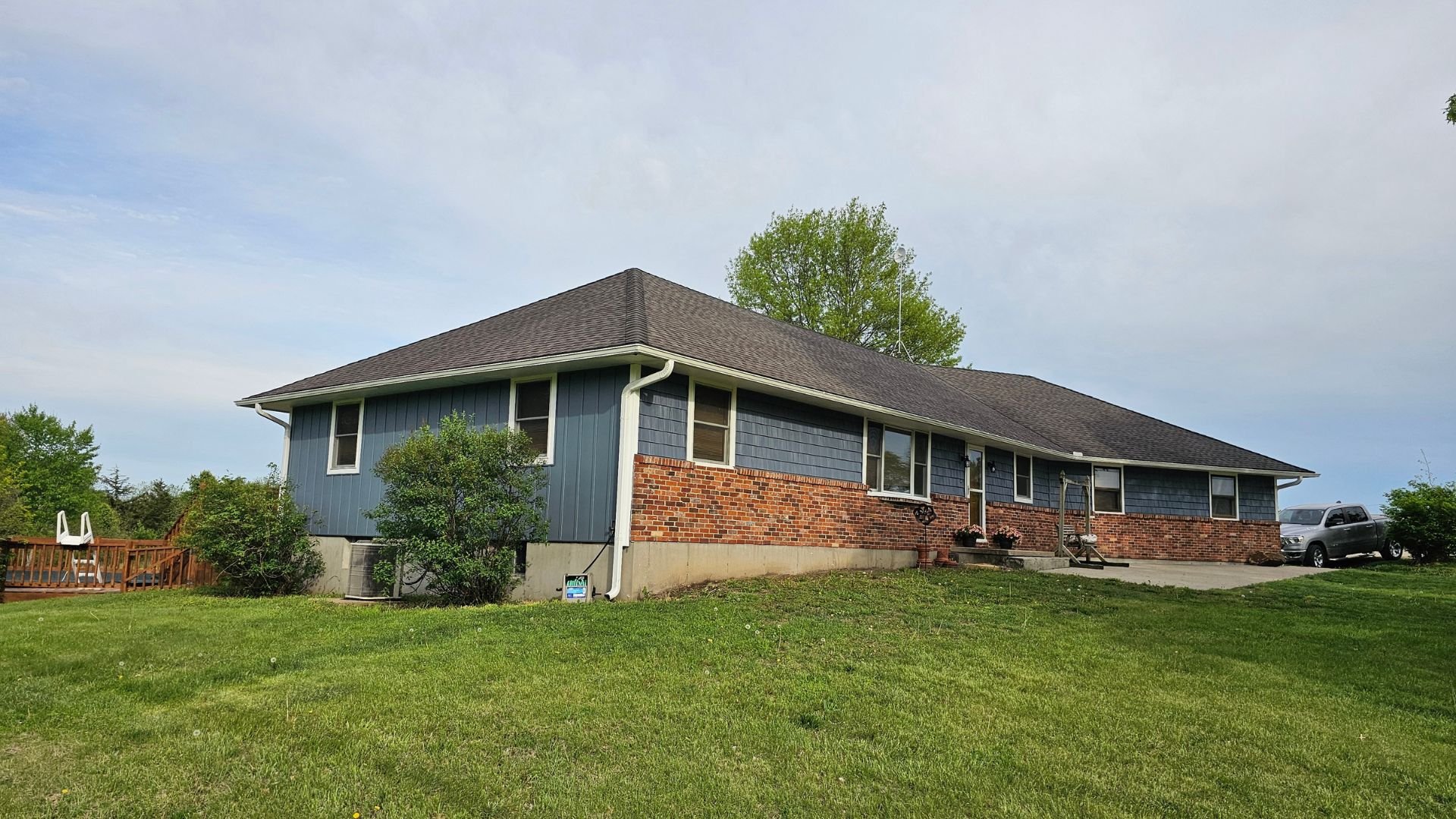 Blue and brick ranch-style house with green lawn on a cloudy day