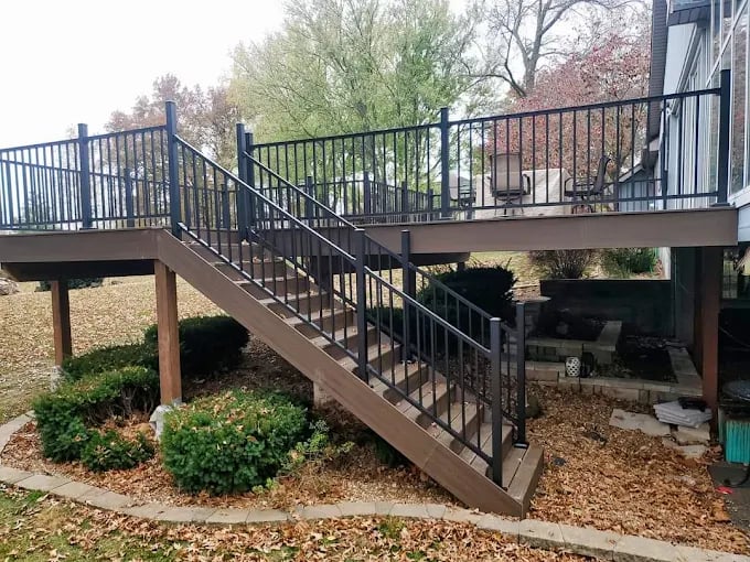 Wooden deck with metal railings and stairs surrounded by autumn leaves