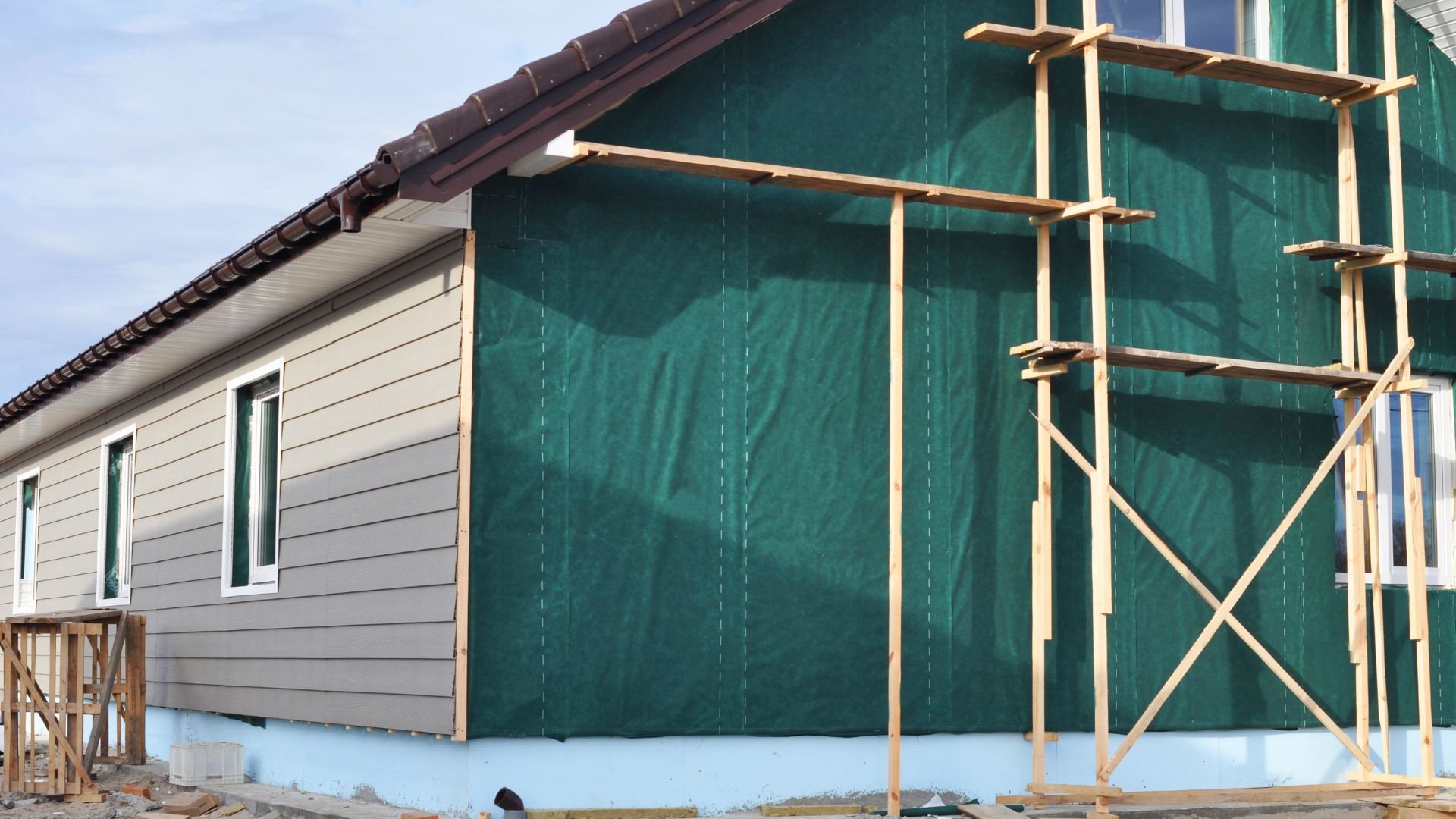 House under construction with green wrap and wooden scaffolding