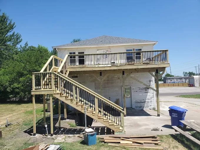 Wooden deck and stairs being constructed on a white two-story building