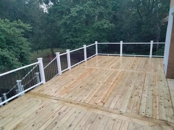 Newly constructed wooden deck with white railings overlooking wooded backyard