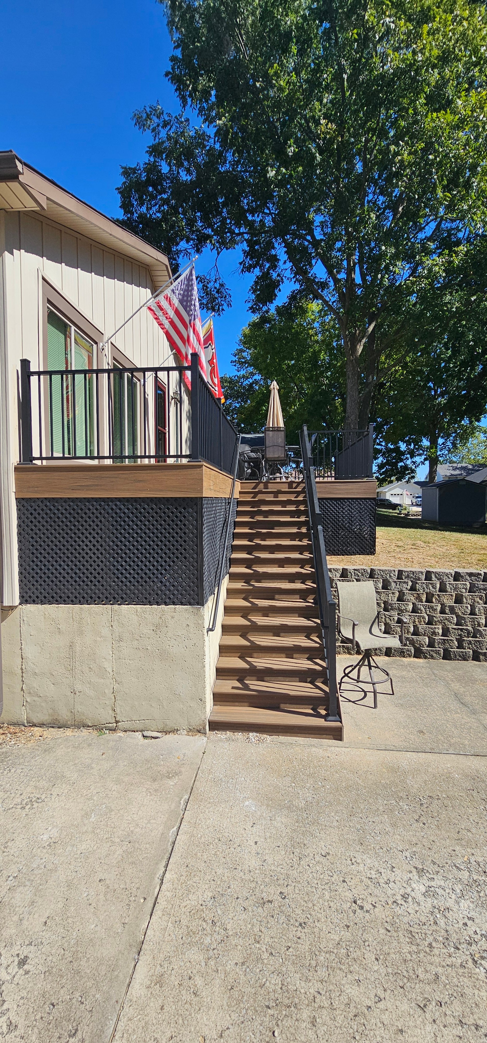 Wooden deck stairs with American flags, leading to a house on a sunny day