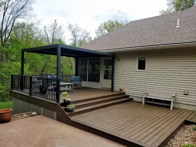 Modern wooden deck with pergola and metal railing near suburban house