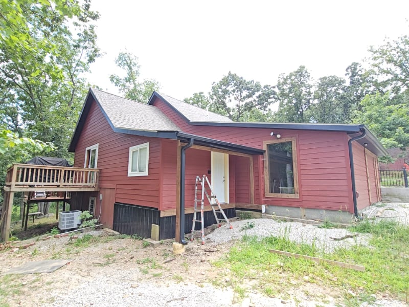 Red wooden house with white trim and ladder during construction or renovation