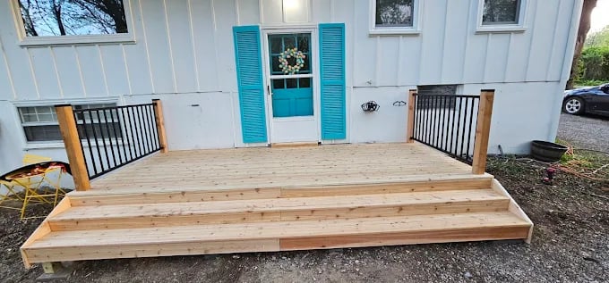New wooden deck with turquoise door and shutters on white farmhouse