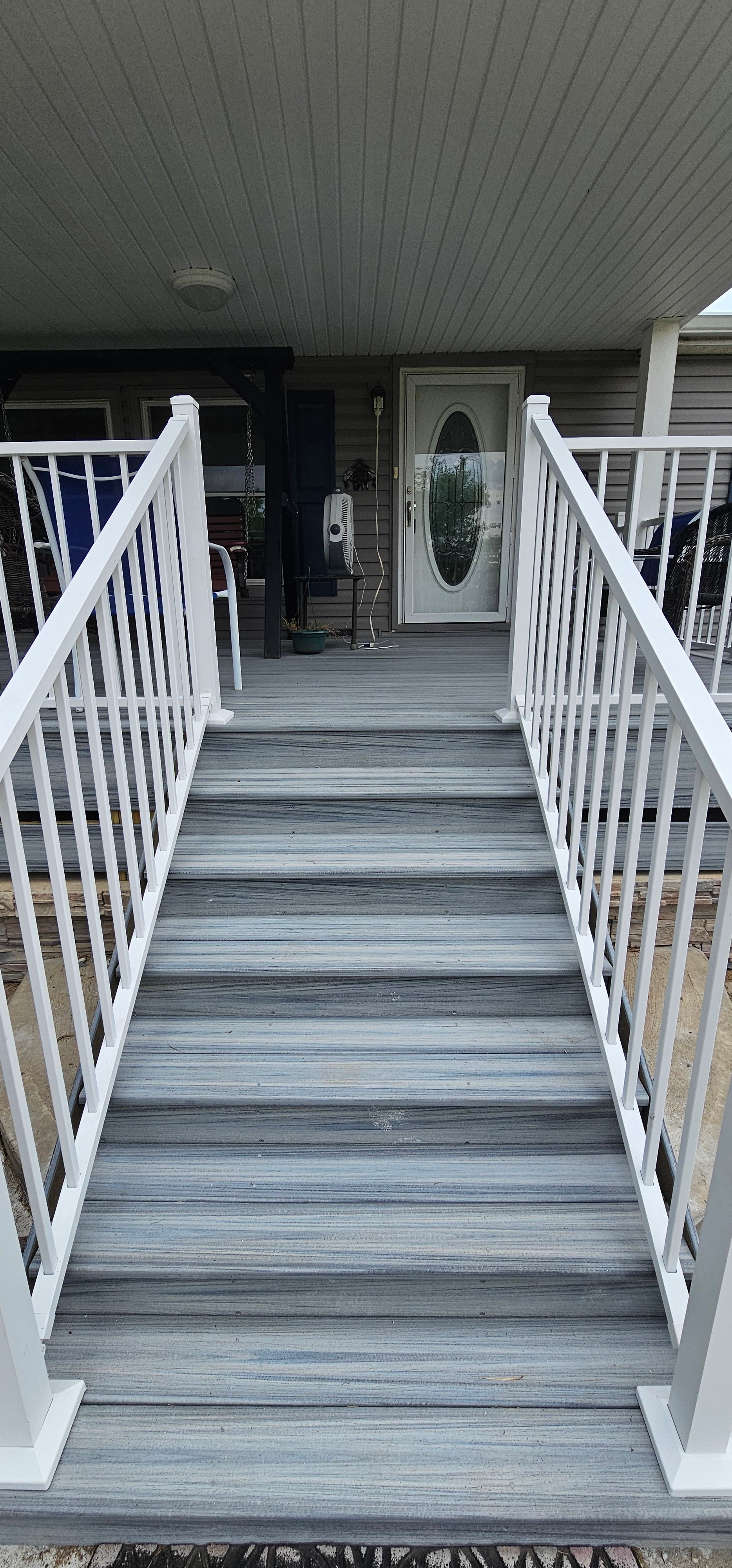 Wheelchair accessible ramp with white railings leading to a front door