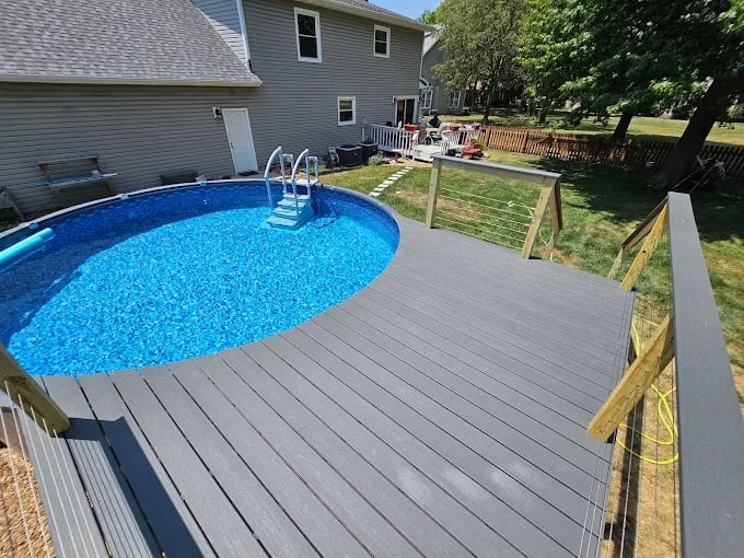 Round blue swimming pool with deck and ladder in suburban backyard